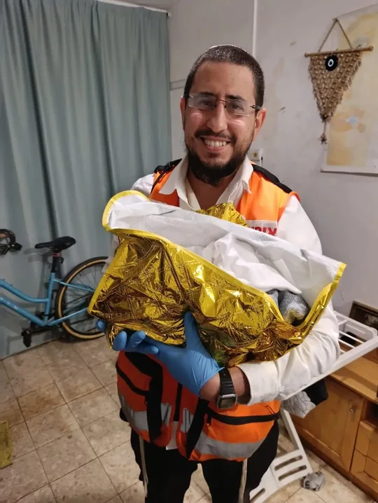 איתמר חמו במדי איחוד הצלה, מחזיק תינוק עטוף בשמיכה