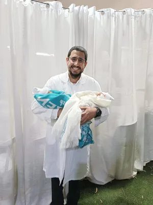 המוהל איתמר חמו בחלוק לבן מחזיק תאומים אחרי הברית